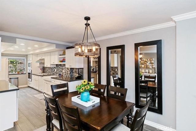 dining room with crown molding, sink, and light wood-type flooring