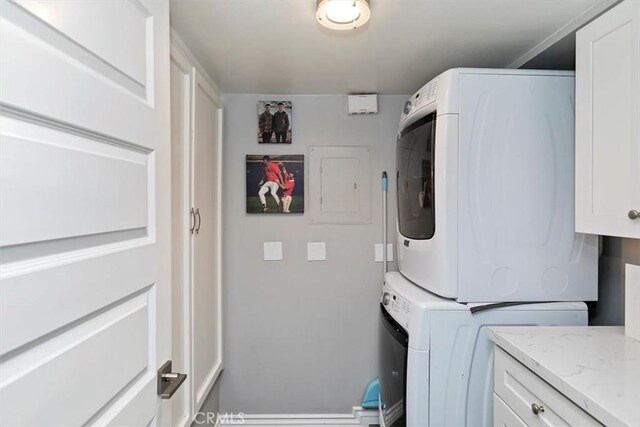 laundry room with cabinets and stacked washing maching and dryer