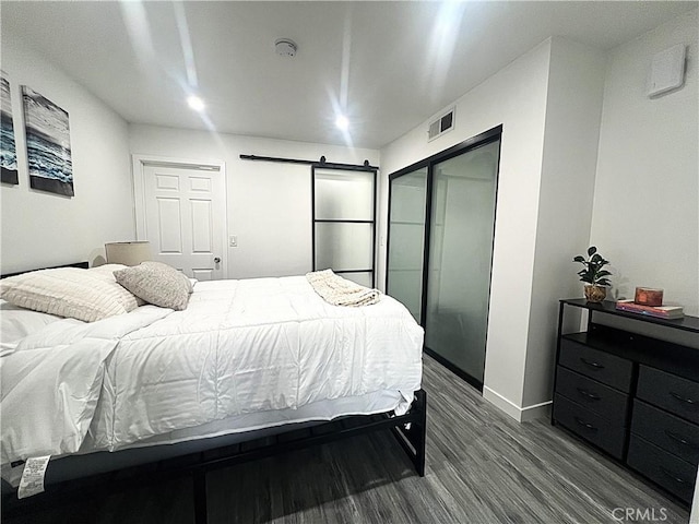 bedroom with wood-type flooring, a barn door, and a closet