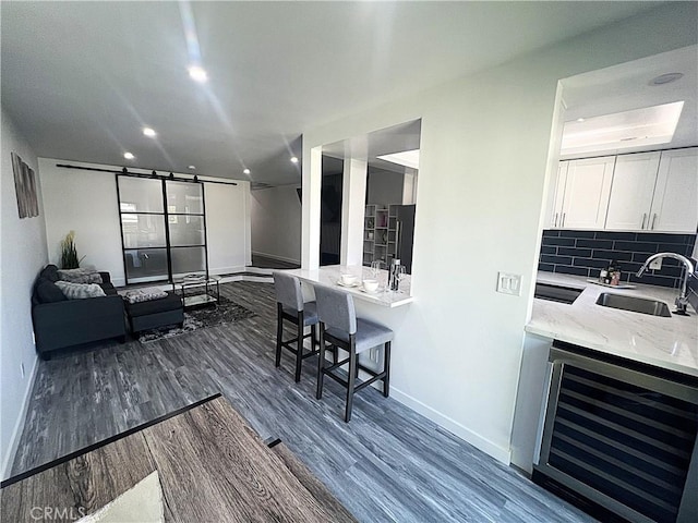 interior space with wine cooler, sink, dark hardwood / wood-style floors, decorative backsplash, and white cabinets