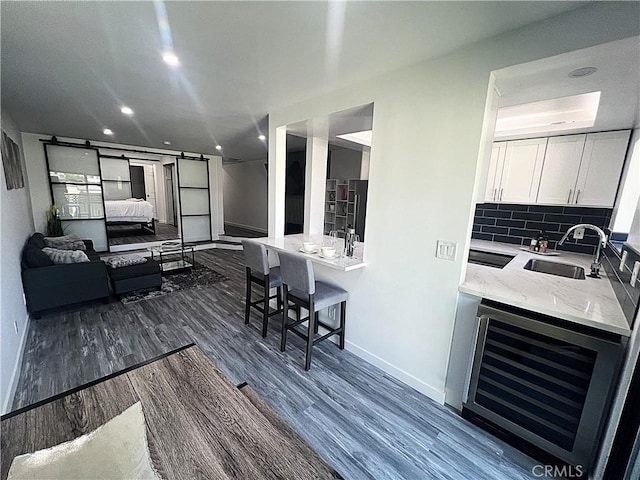 kitchen featuring white cabinetry, sink, wine cooler, decorative backsplash, and a barn door