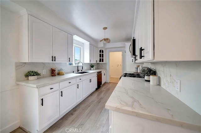 kitchen featuring sink, white cabinetry, light stone counters, dishwashing machine, and backsplash