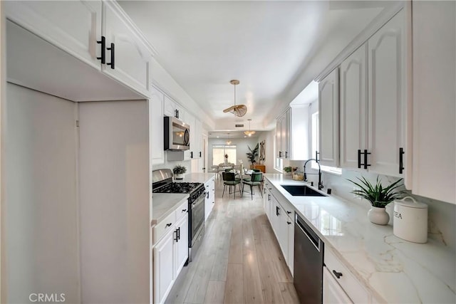 kitchen with light stone counters, sink, white cabinets, and appliances with stainless steel finishes