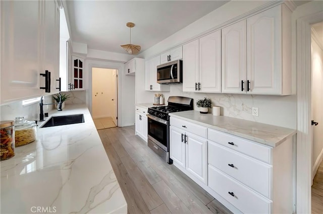 kitchen with appliances with stainless steel finishes, light stone countertops, and white cabinets