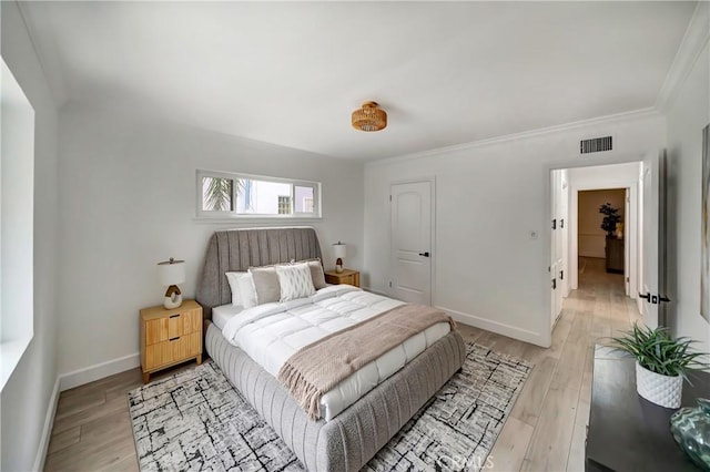 bedroom featuring ornamental molding and light hardwood / wood-style flooring