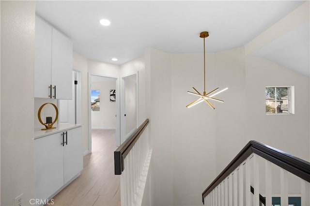 hallway featuring light wood-type flooring, an upstairs landing, and recessed lighting