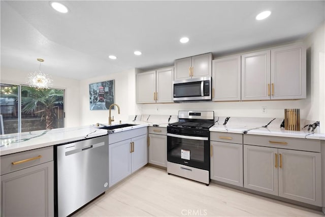 kitchen featuring recessed lighting, gray cabinetry, stainless steel appliances, a sink, and decorative light fixtures