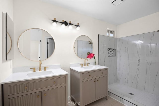 bathroom featuring a shower, two vanities, a sink, and visible vents