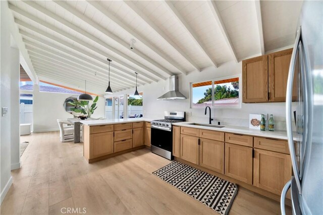 kitchen with sink, appliances with stainless steel finishes, hanging light fixtures, kitchen peninsula, and wall chimney exhaust hood