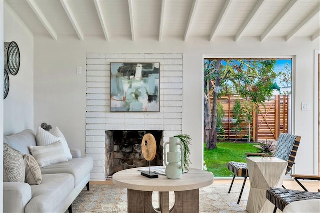 living room featuring beam ceiling, a fireplace, and light hardwood / wood-style flooring