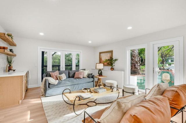 living room with french doors, sink, and light hardwood / wood-style flooring