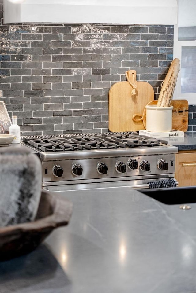 room details featuring tasteful backsplash, stainless steel range, and light brown cabinets