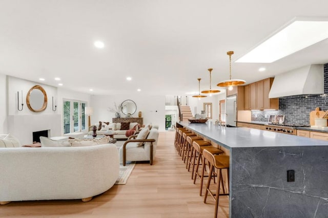 living room with a skylight, sink, and light wood-type flooring