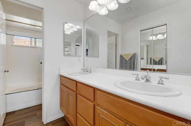 bathroom featuring vanity, wood-type flooring, and enclosed tub / shower combo