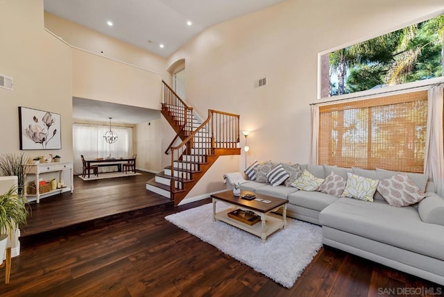 living room with dark wood-type flooring, a chandelier, and a high ceiling