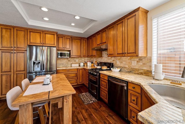 kitchen with a raised ceiling, dark wood-type flooring, backsplash, and black appliances