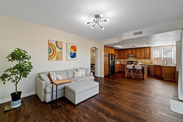 living room featuring dark hardwood / wood-style flooring, sink, and a notable chandelier