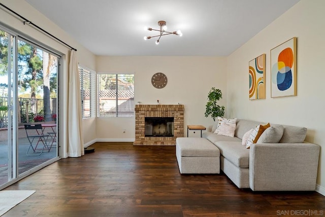 living room with dark wood-type flooring, a fireplace, and a notable chandelier