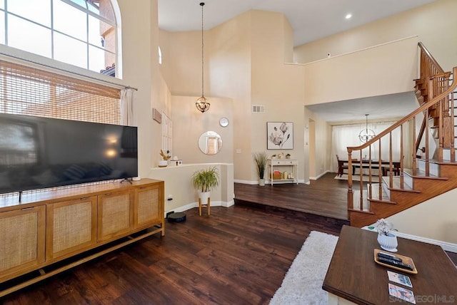 living room with dark wood-type flooring, a notable chandelier, and a towering ceiling