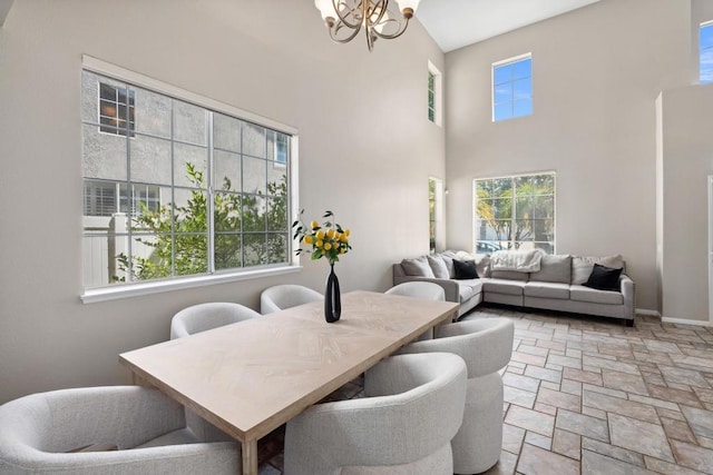 dining room with a healthy amount of sunlight, a high ceiling, and a notable chandelier