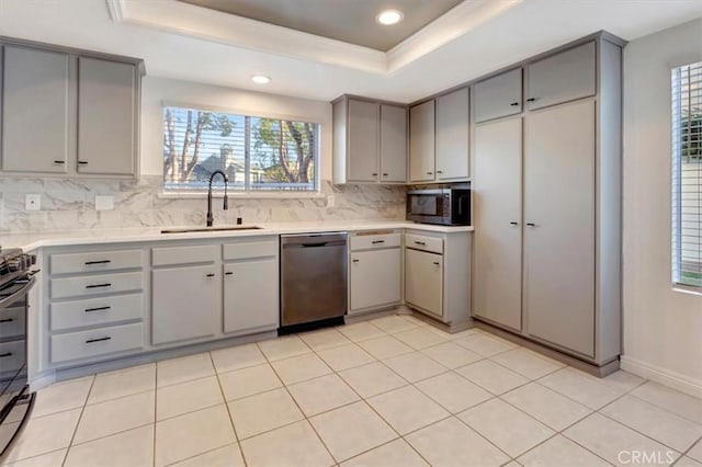 kitchen with gray cabinets, appliances with stainless steel finishes, sink, and a tray ceiling