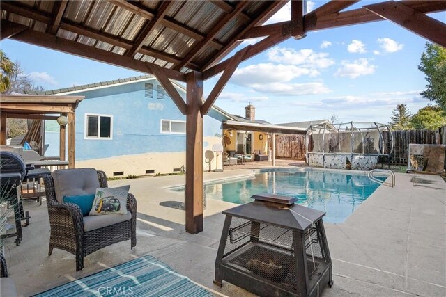 view of pool featuring a patio, a gazebo, and an outdoor living space with a fire pit