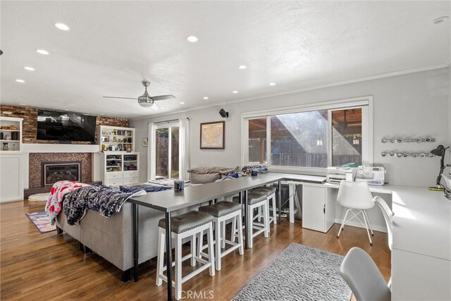 living room featuring ceiling fan, a large fireplace, ornamental molding, and hardwood / wood-style floors