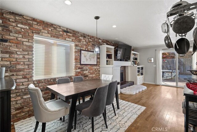 dining area featuring hardwood / wood-style flooring and brick wall