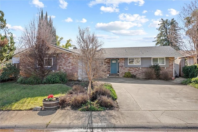 ranch-style home featuring brick siding, driveway, and a front lawn