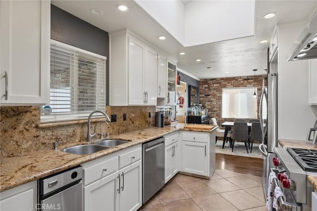 kitchen with decorative backsplash, appliances with stainless steel finishes, light tile patterned flooring, white cabinetry, and a sink