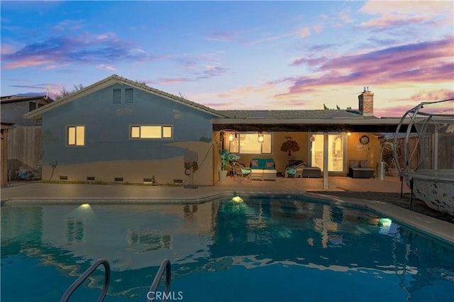 back house at dusk featuring a fenced in pool, a patio area, and outdoor lounge area