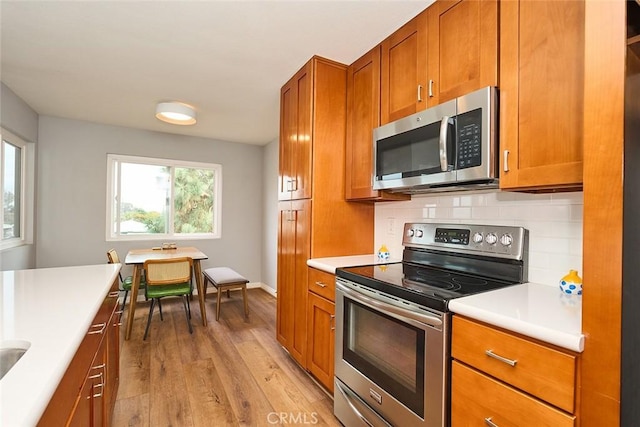 kitchen featuring stainless steel appliances, light wood-type flooring, and backsplash