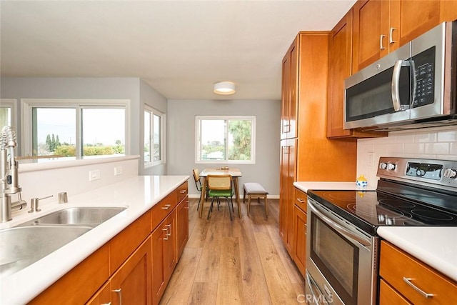 kitchen featuring stainless steel appliances, tasteful backsplash, sink, and light hardwood / wood-style floors