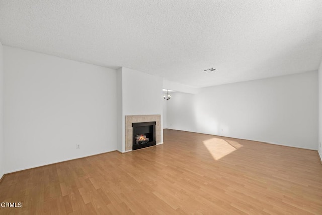 unfurnished living room with a textured ceiling, a fireplace, and light hardwood / wood-style floors