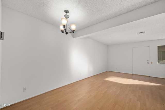 unfurnished room with an inviting chandelier, hardwood / wood-style floors, and a textured ceiling