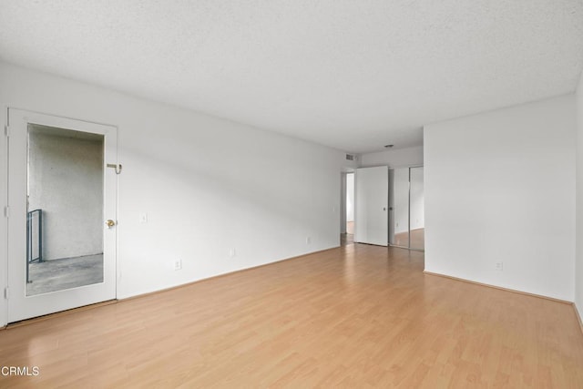 empty room with light hardwood / wood-style floors and a textured ceiling