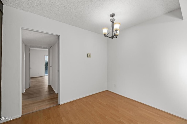 spare room with hardwood / wood-style flooring, a chandelier, and a textured ceiling