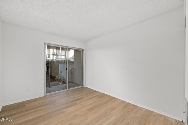 spare room featuring light hardwood / wood-style floors and a textured ceiling