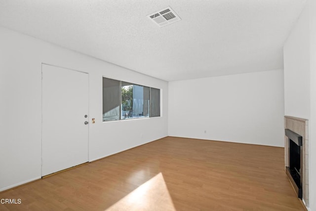 unfurnished living room with wood-type flooring and a textured ceiling