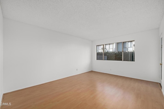 unfurnished room with hardwood / wood-style floors and a textured ceiling