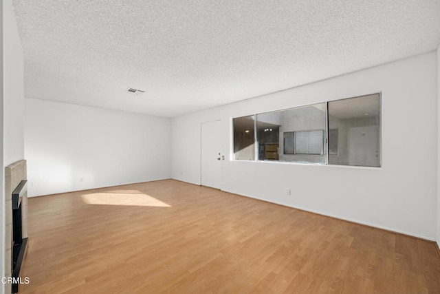 spare room with a textured ceiling, wood finished floors, and visible vents