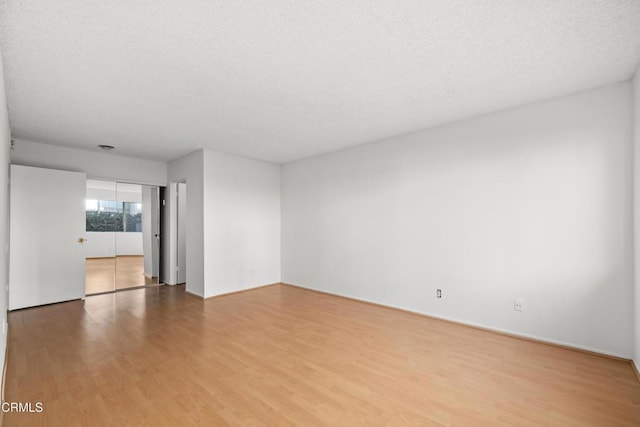 unfurnished room with a textured ceiling and wood finished floors