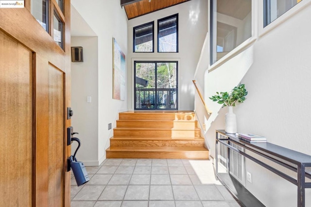 foyer entrance with light tile patterned floors and a towering ceiling