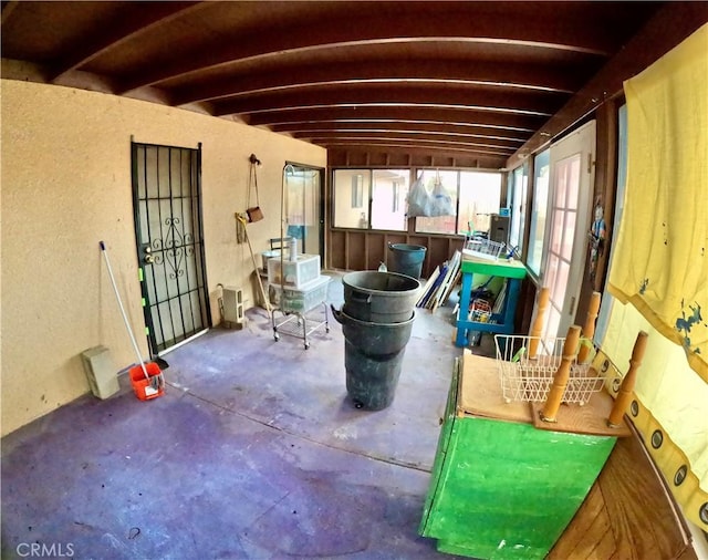 miscellaneous room with beamed ceiling and concrete floors