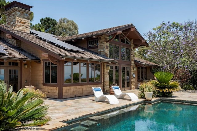 back of house featuring a patio area and solar panels