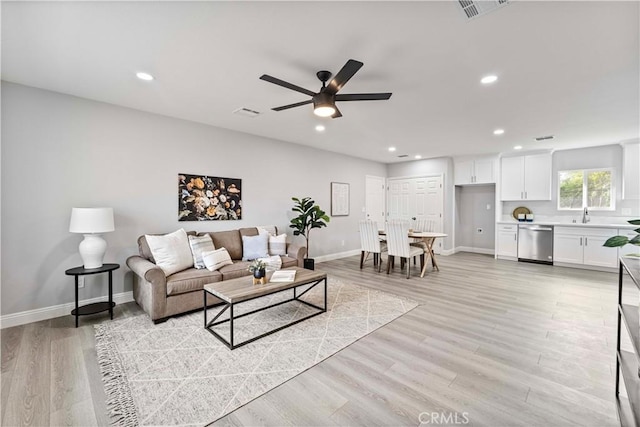 living room featuring ceiling fan, sink, and light hardwood / wood-style flooring