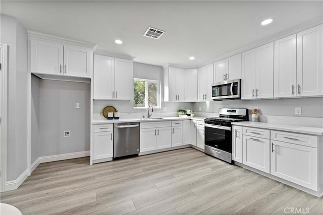 kitchen featuring appliances with stainless steel finishes, light hardwood / wood-style floors, sink, and white cabinets