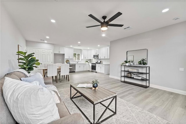 living room featuring light hardwood / wood-style floors and ceiling fan