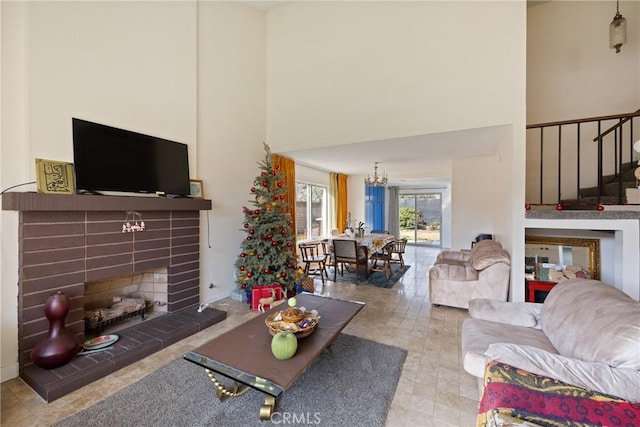 living room with a towering ceiling, a tiled fireplace, and a notable chandelier