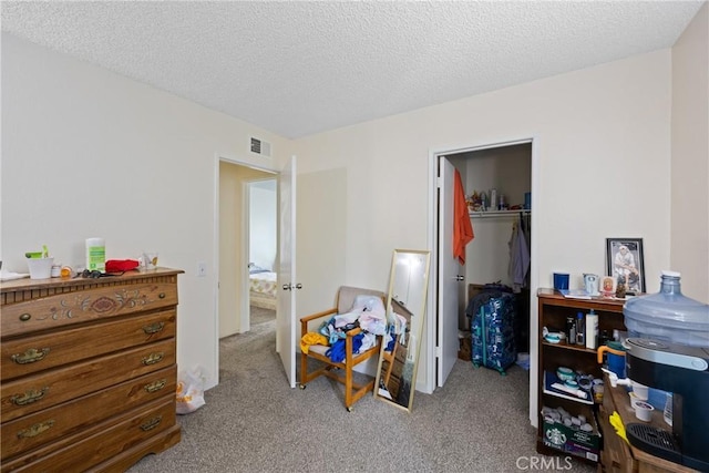 carpeted bedroom featuring a walk in closet, a textured ceiling, and a closet